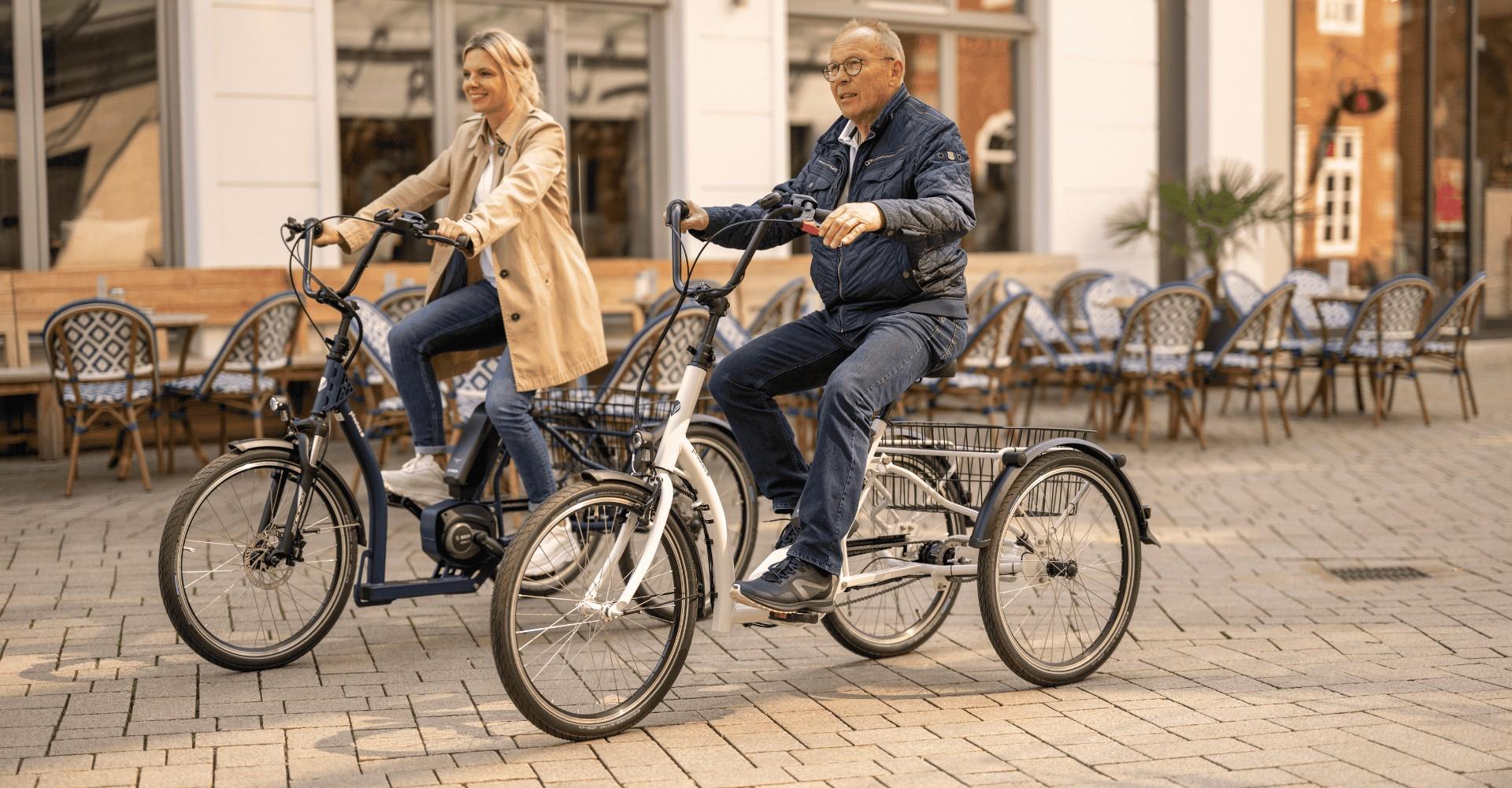 Zwei Personen fahren auf ihren pfautec Dreirädern durch die Stadt