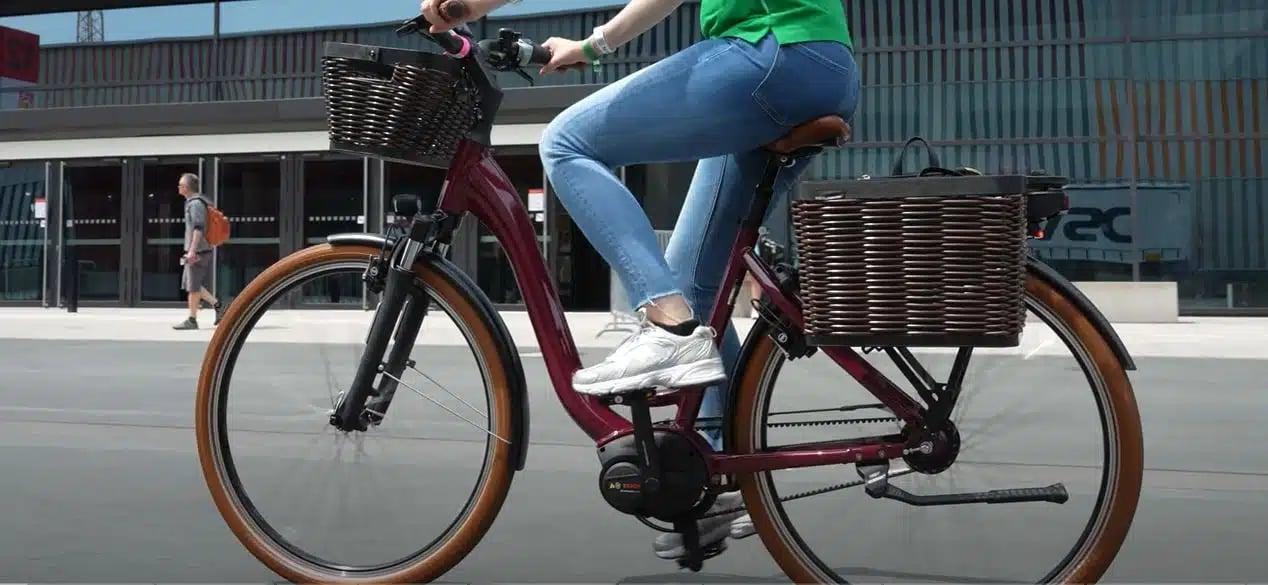 Frau auf E-Bike mit Körben fährt auf der Straße