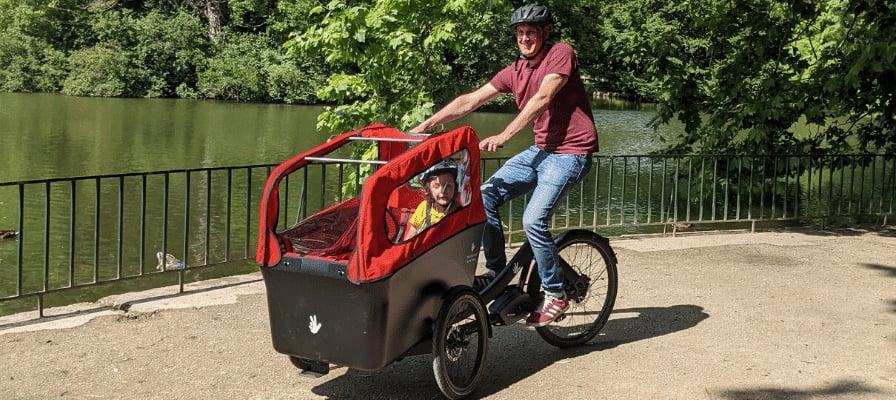 Triobike Boxter Lastenrad mit Kind am Seeufer