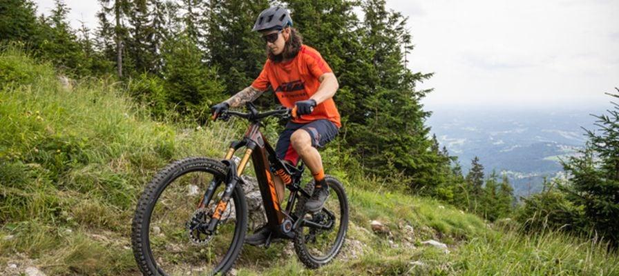 Mann testet KTM E-Mountainbike auf Waldweg in den Bergen