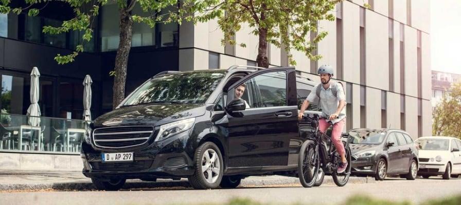 Mann mit E-Bike neben geparktem Auto auf städtischer Straße