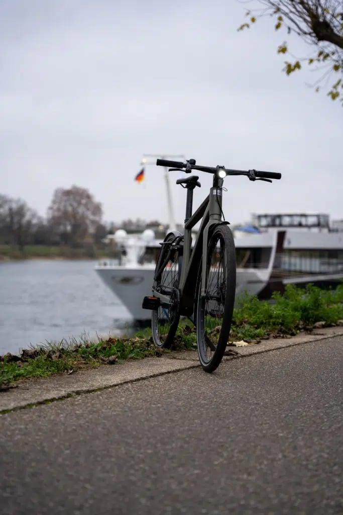 E-Bike vor Flusslandschaft mit Schiff im Hintergrund