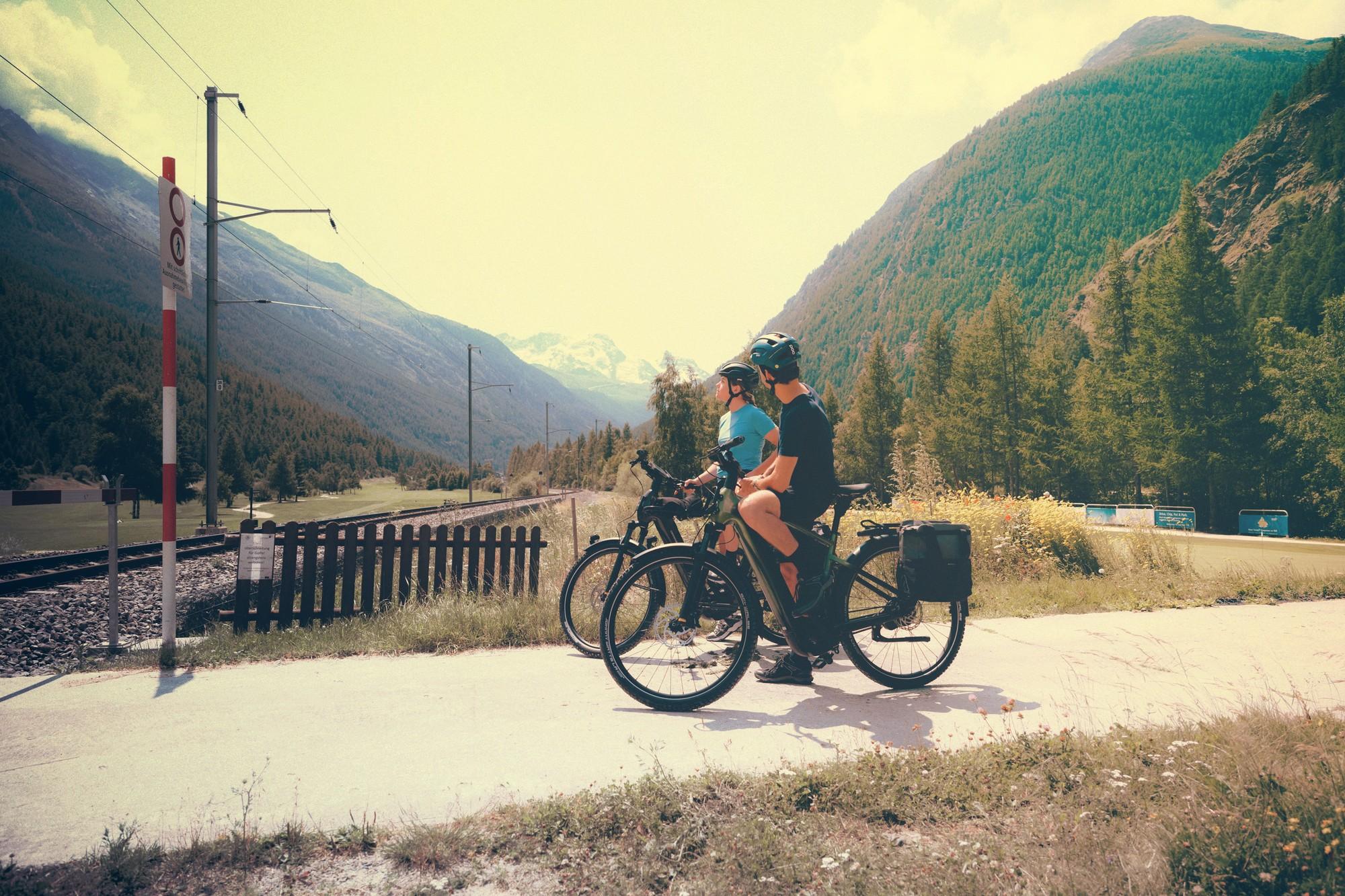 Zwei Personen stehen vor einem Bahnübergang mit Cannondale Tesoro e-Bikes