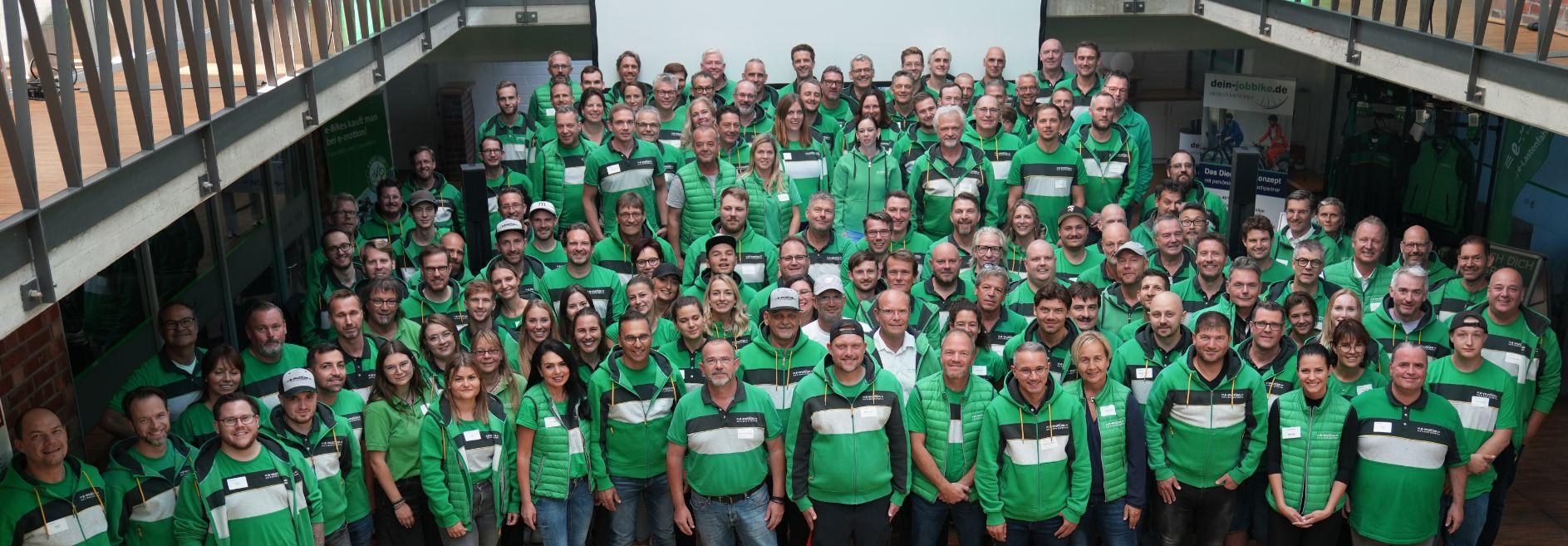 Das emotion Team in grünen Outfits posiert für ein Gruppenfoto. Perfekt für gemeinschaftlichen Teamgeist und Marken