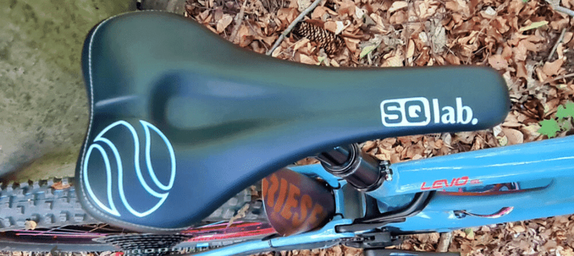 SQlab Sattel auf einem türkisblauen Mountainbike im Wald, fotografiert von oben auf Sitz und Rahmen.
