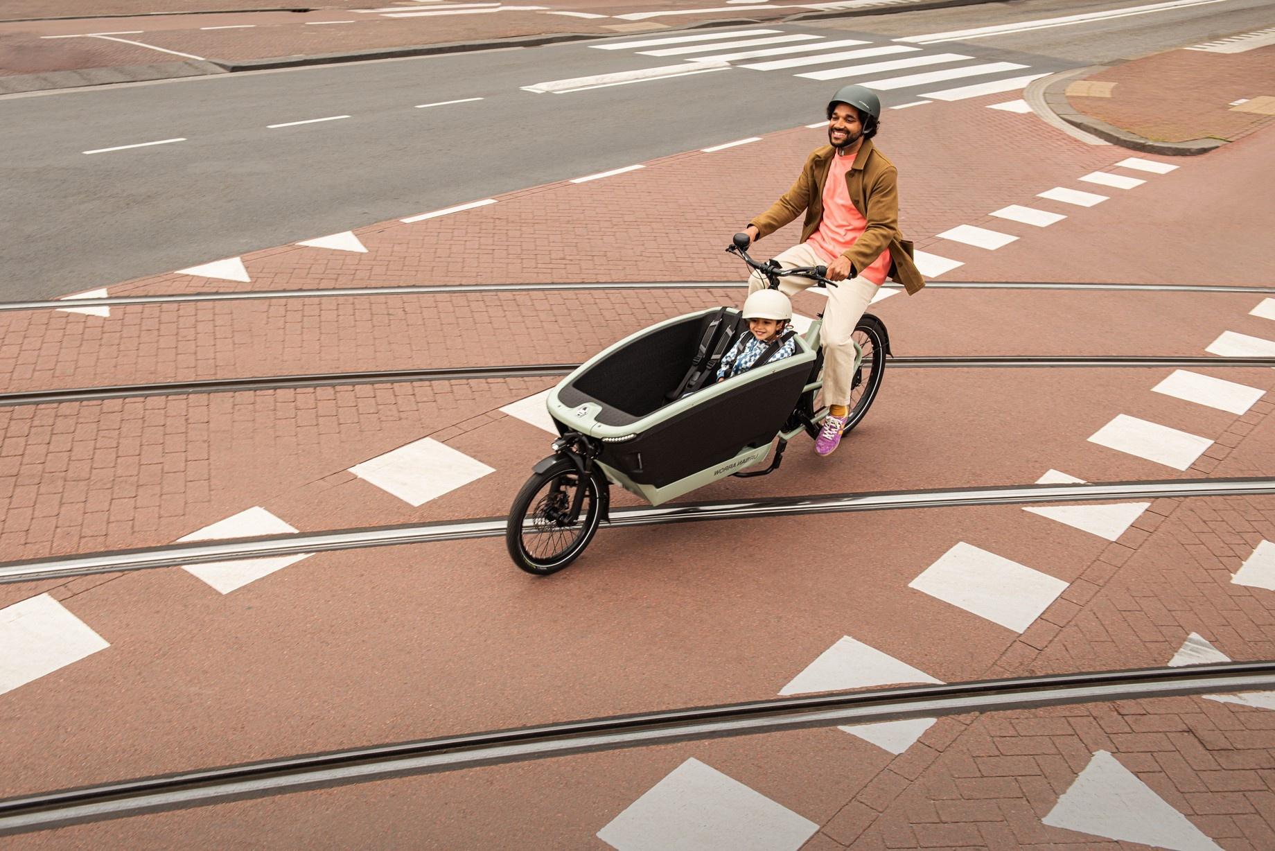 Ein Mann mit Kind fährt im Urban Arrow FamilyNext über Gleise