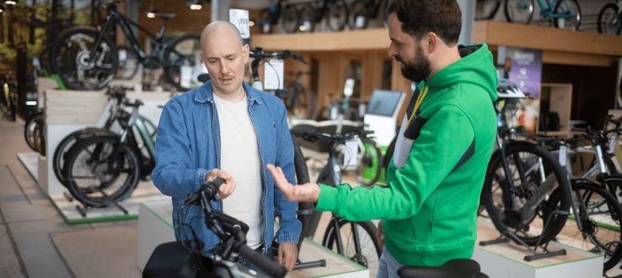 Zwei Männer diskutieren in einem Fahrradgeschäft vor E-Bikes