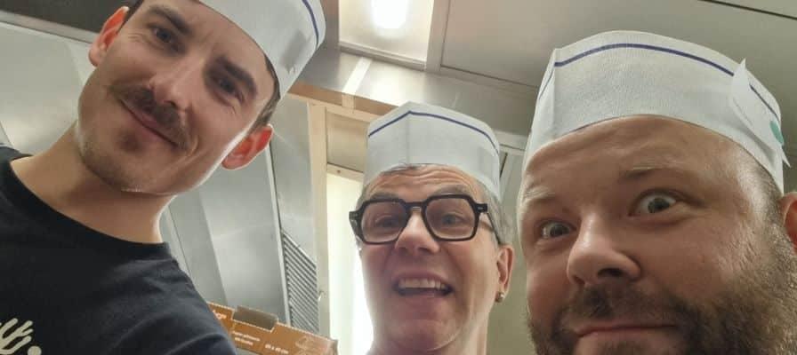 Drei Männer mit Papierhüten in einer Küche