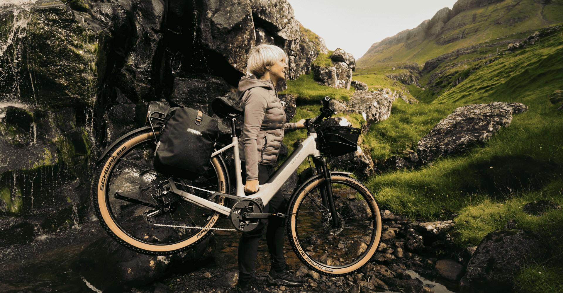 Eine Frau trägt ein Kalkhoff e-Bike in den Bergen