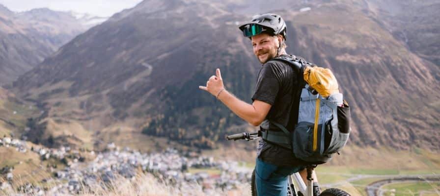 Mann mit Helm auf E-Mountainbike vor Berglandschaft