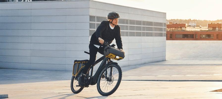 Mann fährt E-Bike auf urbanem Platz bei Sonnenuntergang