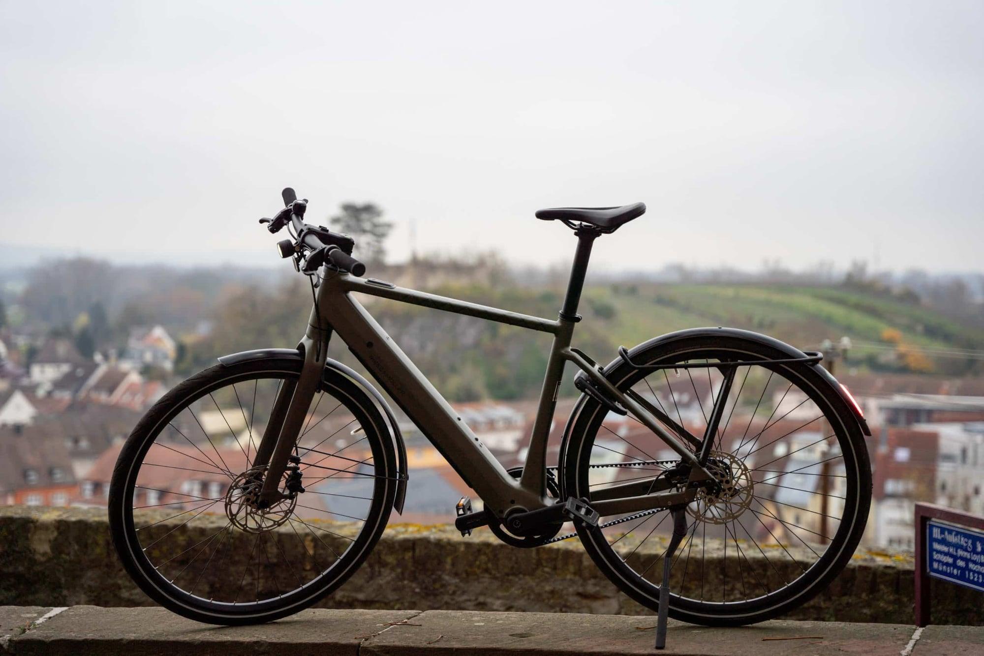 Modernes E-Bike vor städtischer Kulisse mit Hügeln im Hintergrund