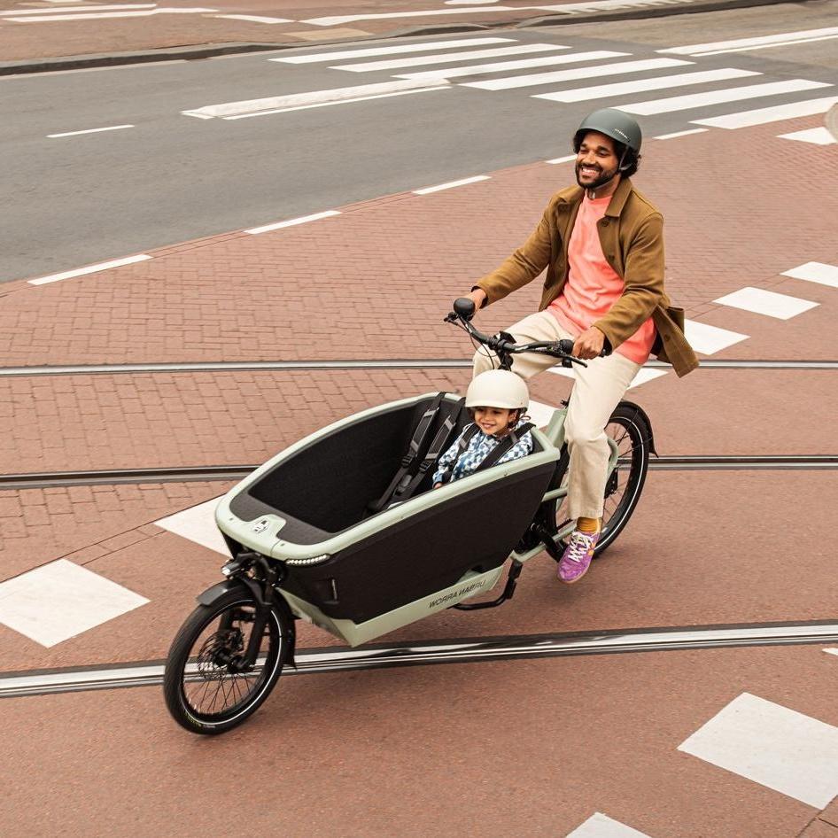 Ein Mann mit Kind fährt im Urban Arrow FamilyNext über Gleise