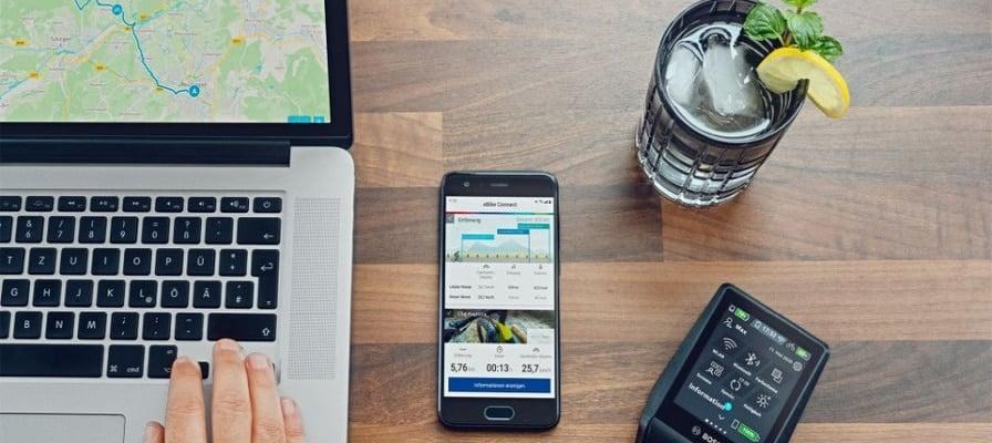 Laptop, Smartphone mit eBike-App und Bosch eBike-Display auf Holztisch