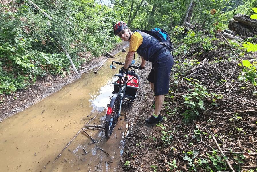Person mit E-Bike auf schlammigem Waldweg