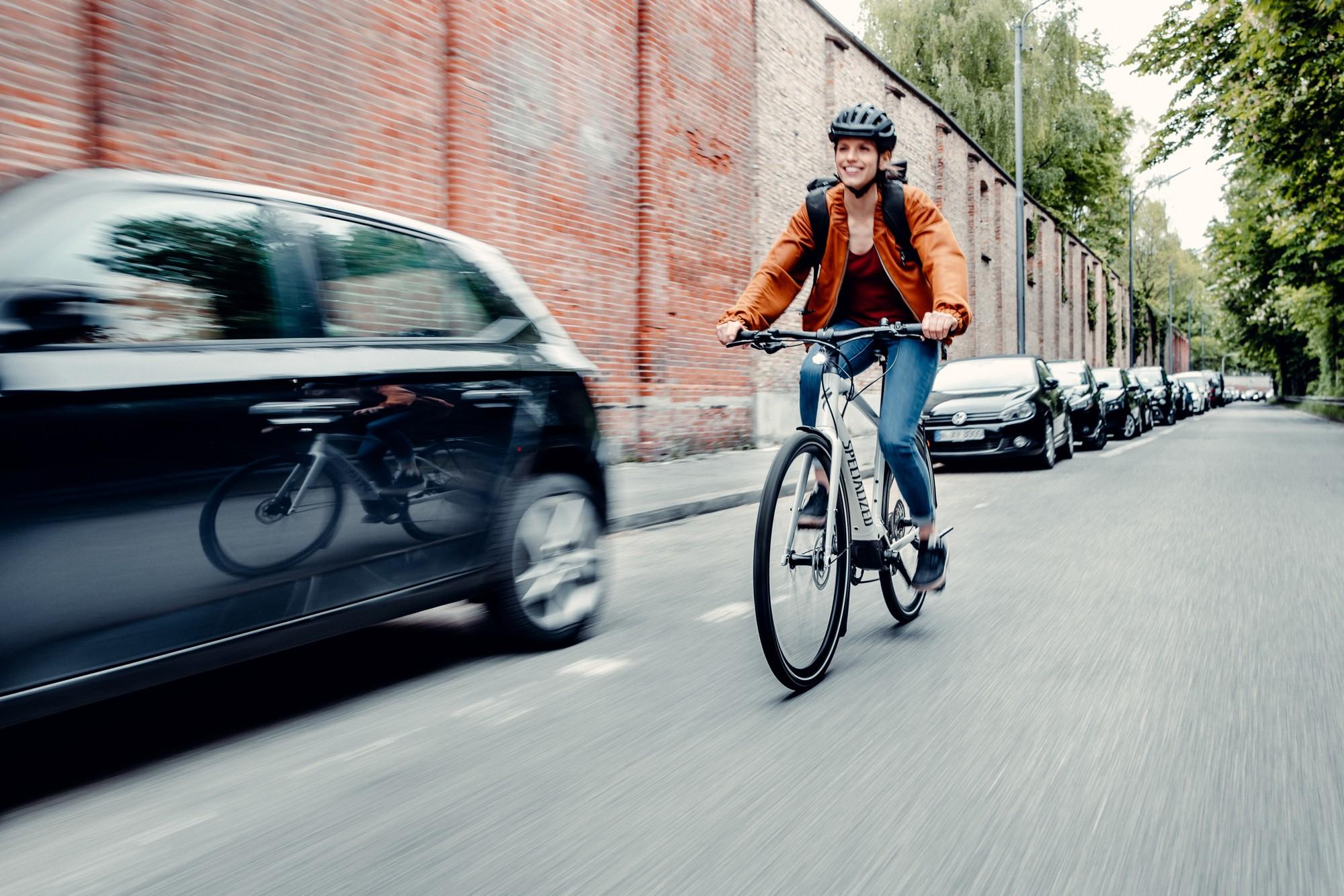 Eine Frau fährt auf dem Specialized e-Bike an Autos vorbei