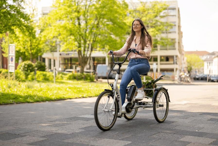 Frau auf Dreirad fährt durch städtischen Park