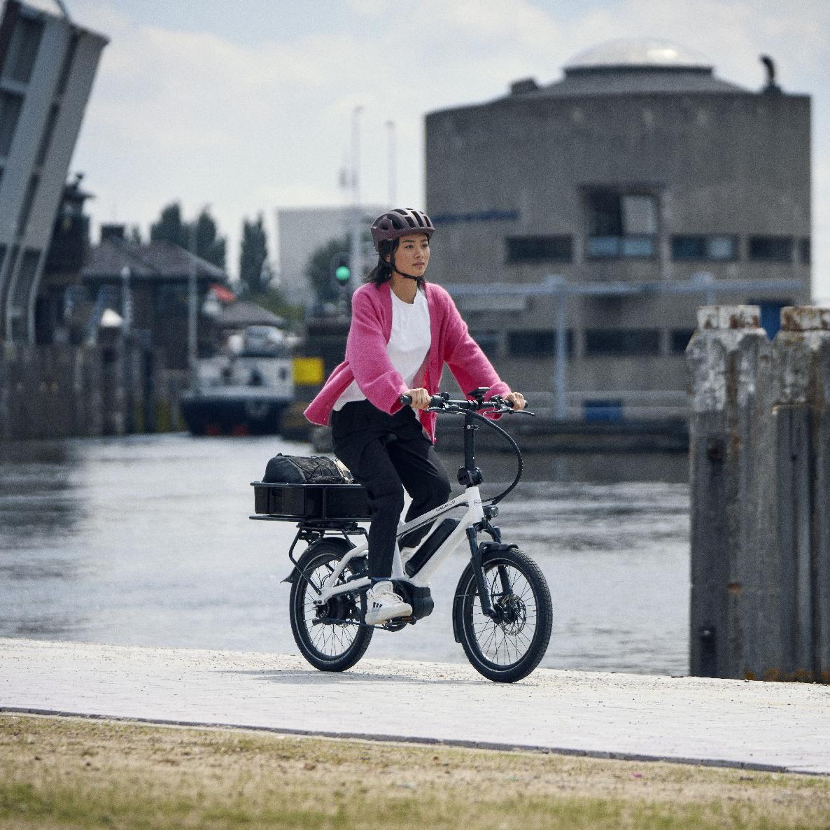 Eine Frau fährt auf dem Riese und Müller Tinker am Wasser entlang