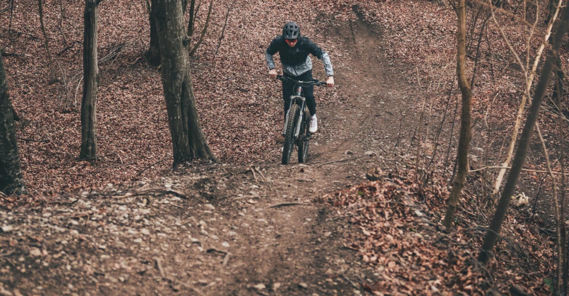 Ein Mann fährt mit dem Raymon TrailRay den Waldweg entlang