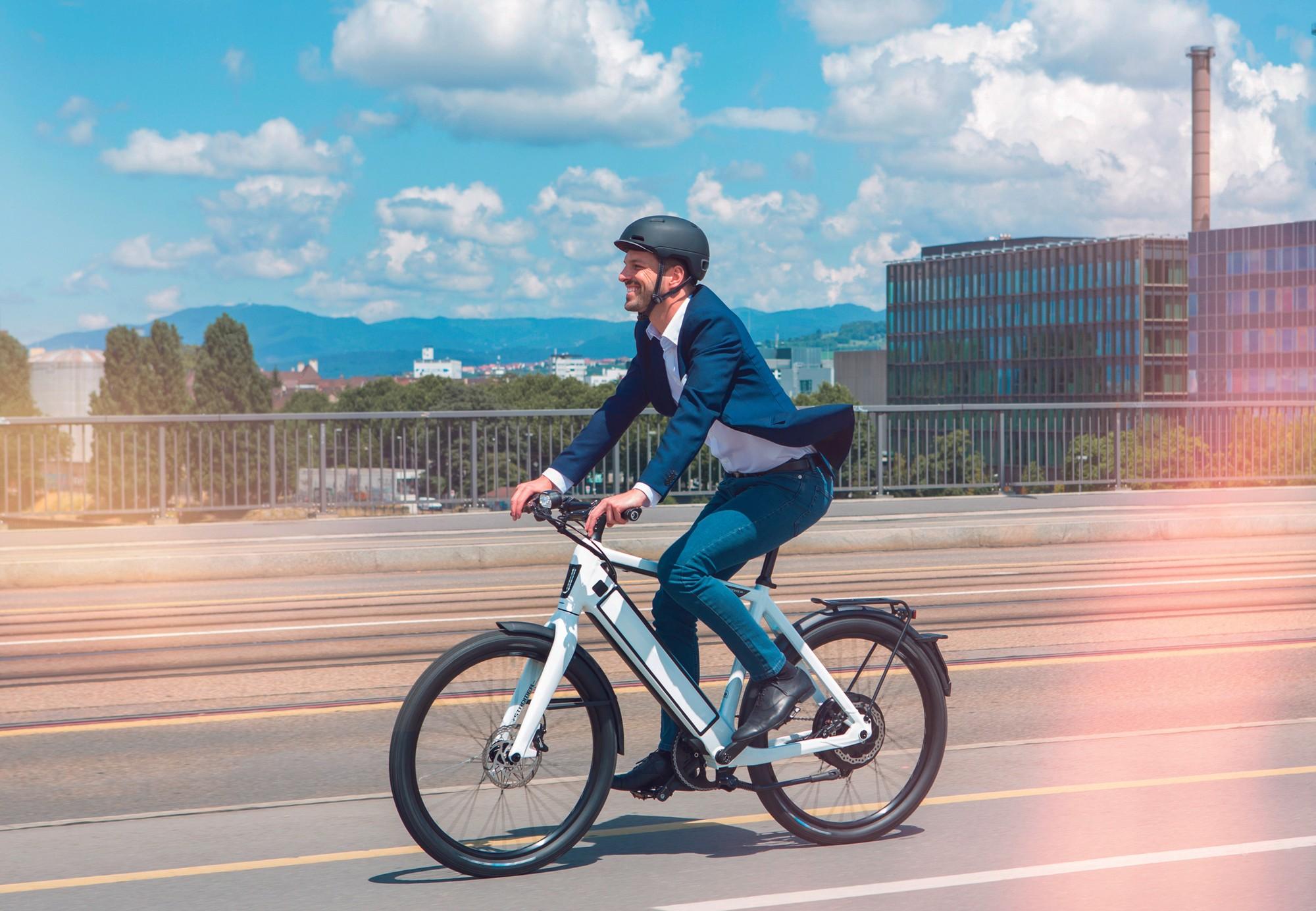 Ein Stromer MY18 ST2 Sport E-Bike in der Farbe Weiß, das von einem Radfahrer in einem Anzug gefahren wird.