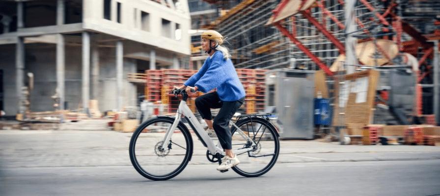 Frau fÀhrt E-Bike vor Baustelle in der Stadt