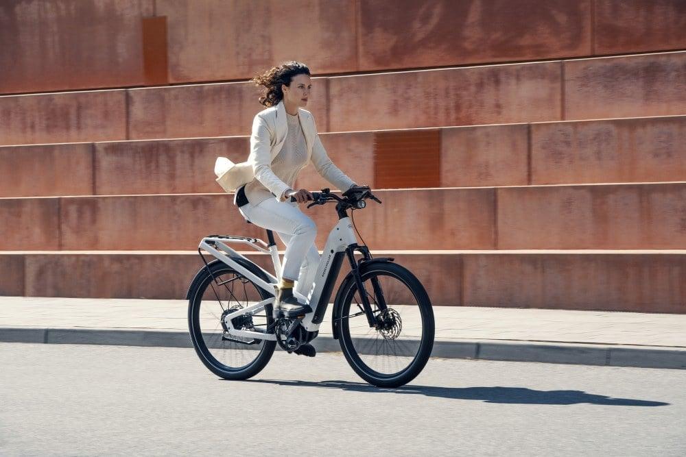 Frau fährt Riese & Müller E-Bike vor moderner Architektur