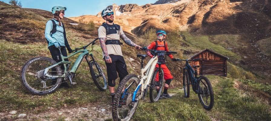 Gruppe von Mountainbikern auf einem Bergpfad mit Holzhütte im Hintergrund