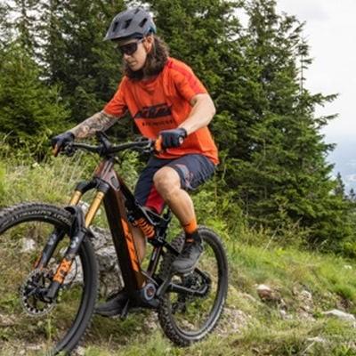 Mann testet KTM E-Mountainbike auf Waldweg in den Bergen