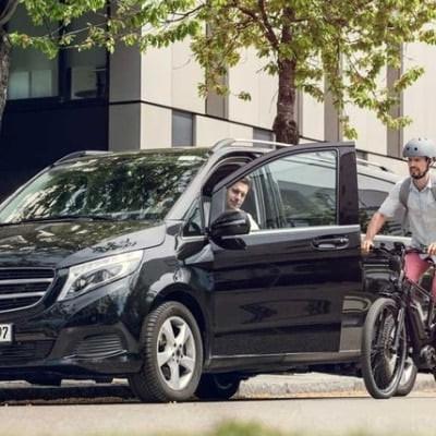 Mann mit E-Bike neben geparktem Auto auf städtischer Straße