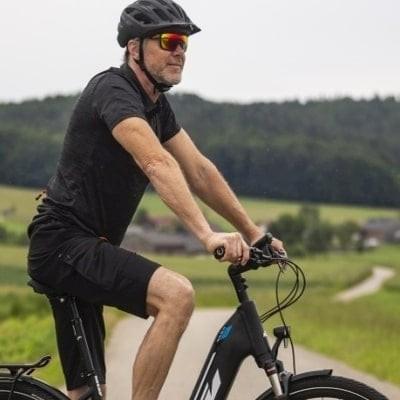 Mann auf KTM E-Bike auf ländlicher Straße mit Helm