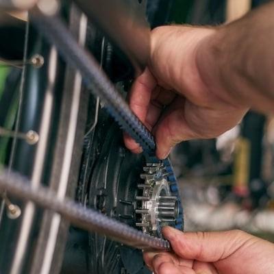 Fahrradmechaniker justiert Riemenantrieb an Hinterrad