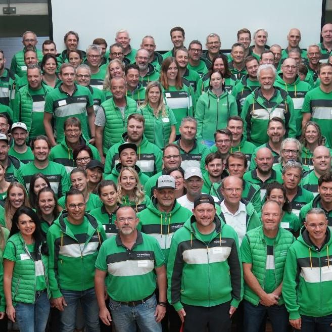 Das emotion Team in grünen Outfits posiert für ein Gruppenfoto. Perfekt für gemeinschaftlichen Teamgeist und Marken