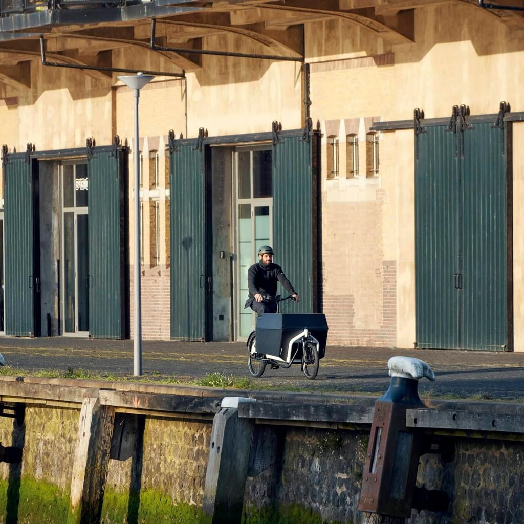 Person fährt Lastenrad vor Industriegebäude