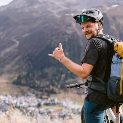 Mann mit Helm auf E-Mountainbike vor Berglandschaft