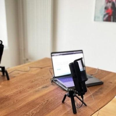 Zwei Männer im Gespräch mit Mikrofonen und Laptops bei einem Podcast
