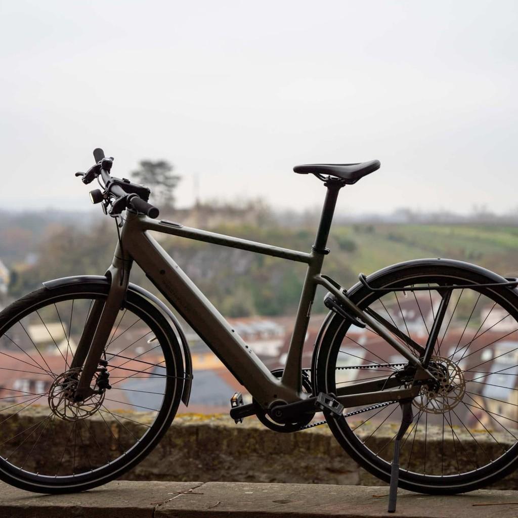 Modernes E-Bike vor städtischer Kulisse mit Hügeln im Hintergrund