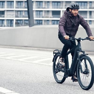 Mann fährt Riese & Müller Charger4 E-Bike auf einer Brücke