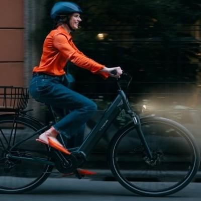Frau fährt Bianchi T-Tronik E-Bike durch Stadt bei Nacht