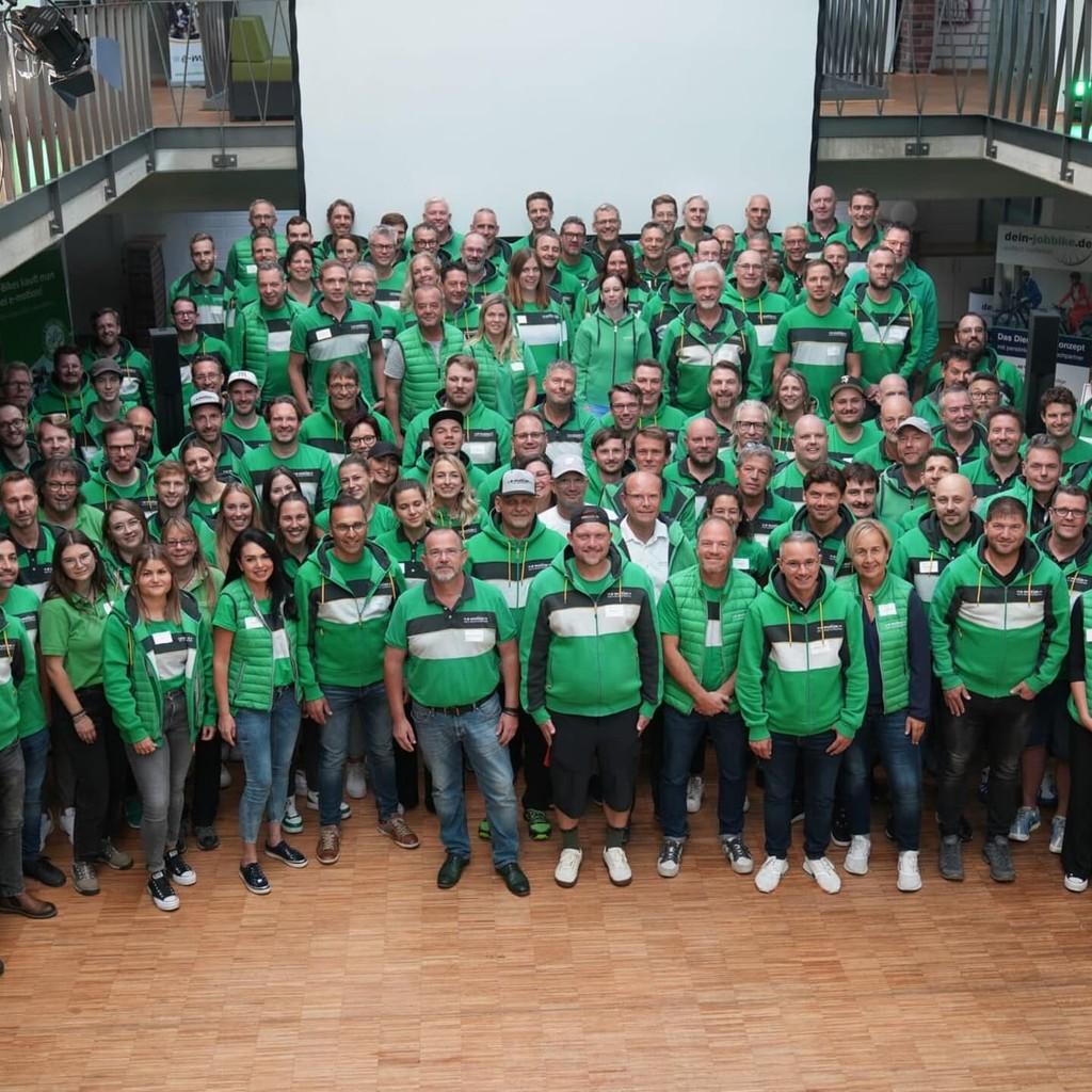 Gruppenfoto von Personen in grünen Hemden in einem großen Raum
