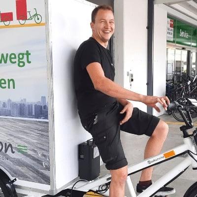 Mann auf e-motion Lastenrad vor einem Lieferwagen