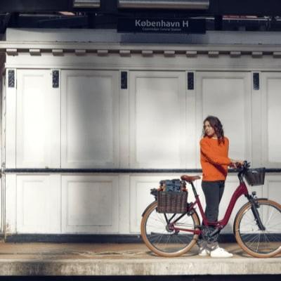 Frau mit E-Bike auf Bahnsteig vor rotem Zug
