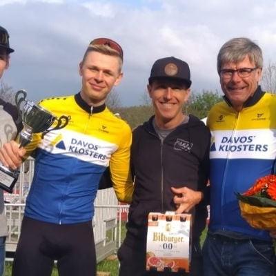 Gruppe von Personen mit Pokal und Blumen bei Outdoor-Event