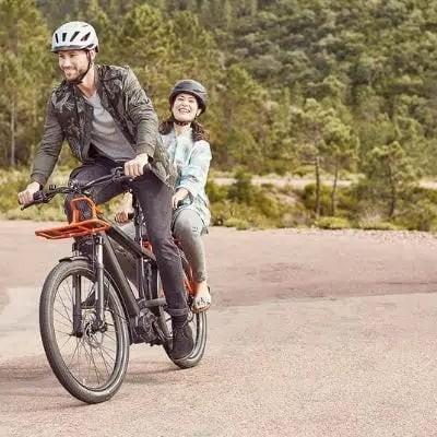 Paar fährt auf E-Bike durch bewaldete Landschaft