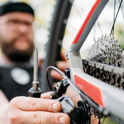 Mann justiert E-Bike-Kettenschaltung im Freien