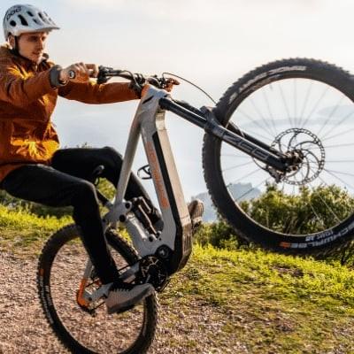 Mann macht Wheelie auf Simplon Rapcon PMAX PINION E-Bike in bergiger Landschaft