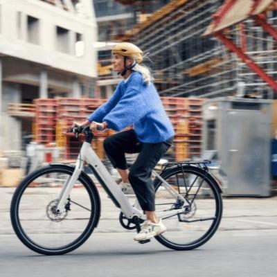 Frau fÀhrt E-Bike vor Baustelle in der Stadt