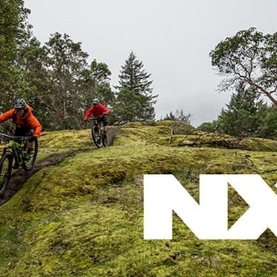 Mountainbiker fahren auf einem Waldweg mit NX-Logo