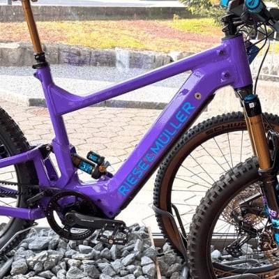 Lila Riese & Müller E-Bike vor Gebäude auf Schotter