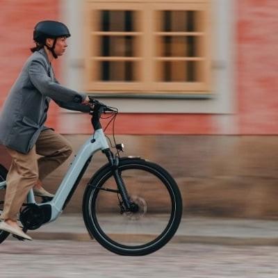 Mann fährt E-Bike vor historischem Gebäude