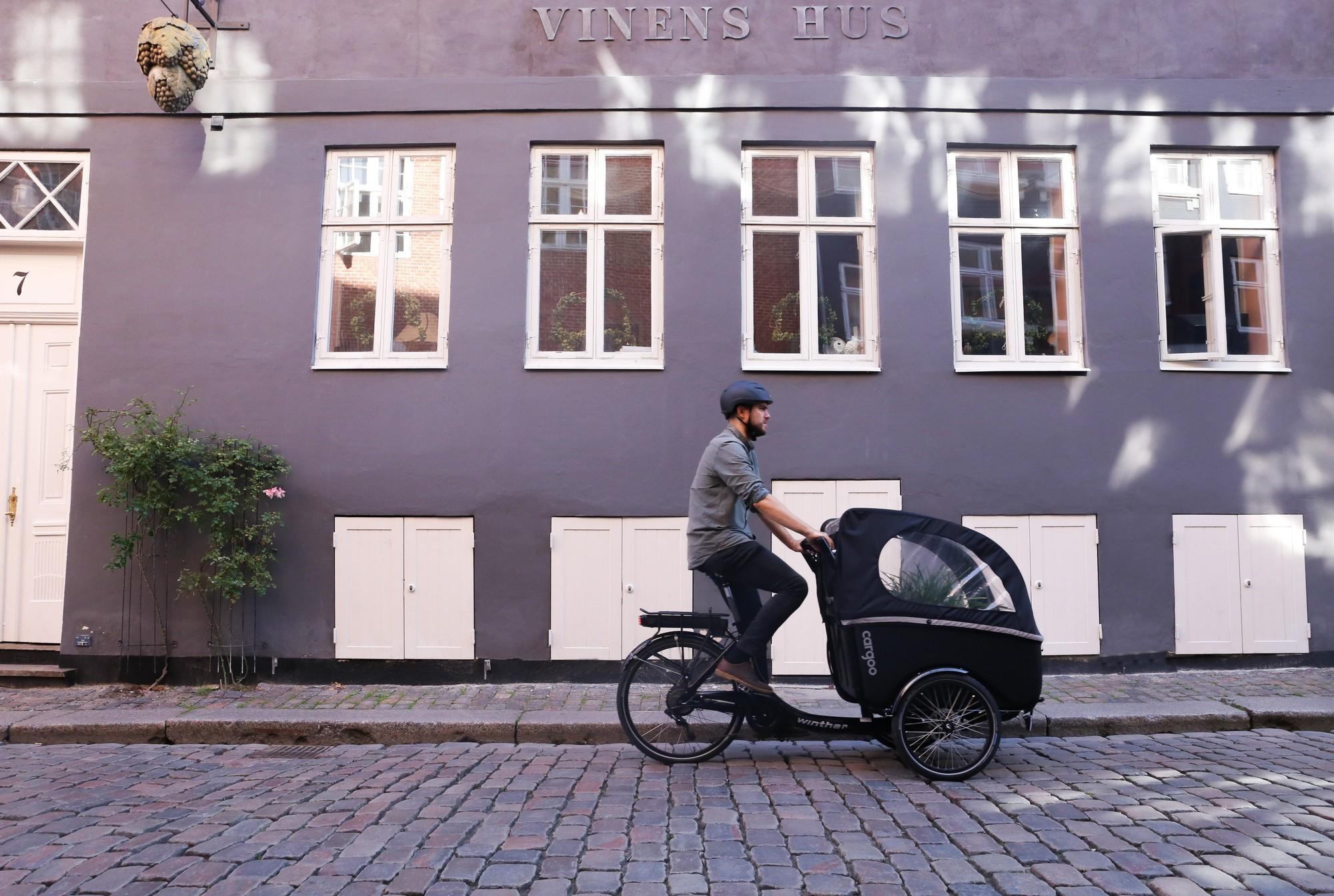 Ein Mann fährt auf dem Winther Cargoo Lastenrad durch die Stadt